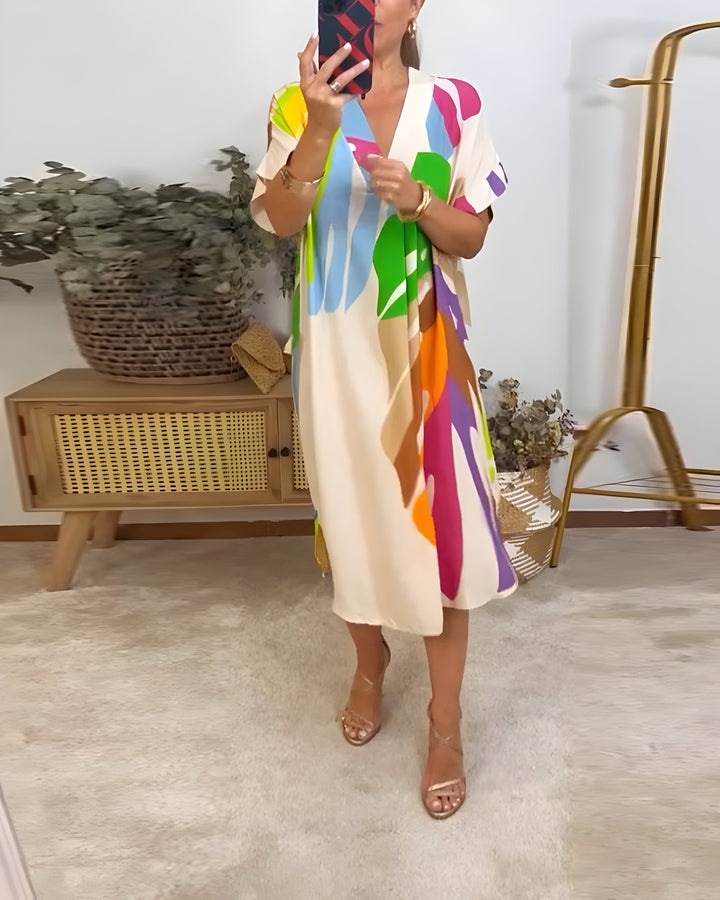 A woman wearing a colourful abstract print dress with a V-neckline and short sleeves.