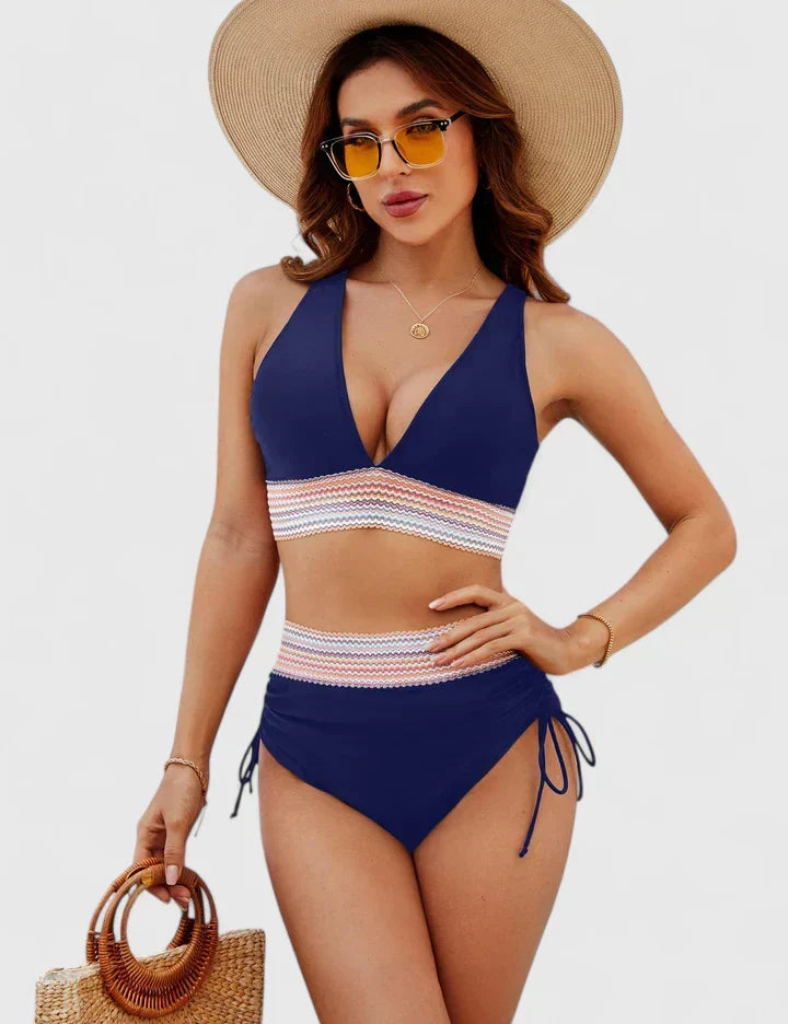 A woman wearing an elegant matching bikini set with a bold print, relaxed and confident on the beach.