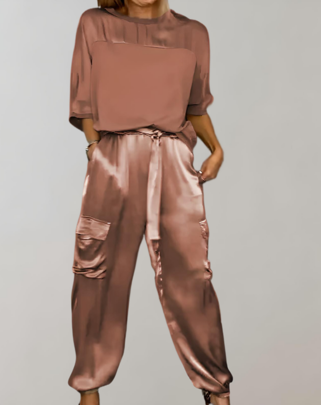 A woman wearing a silky-finish cargo top and pants lounge set with pockets.
