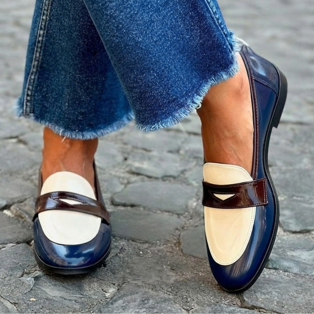 A woman wearing two-tone contrast loafers on a bright street.