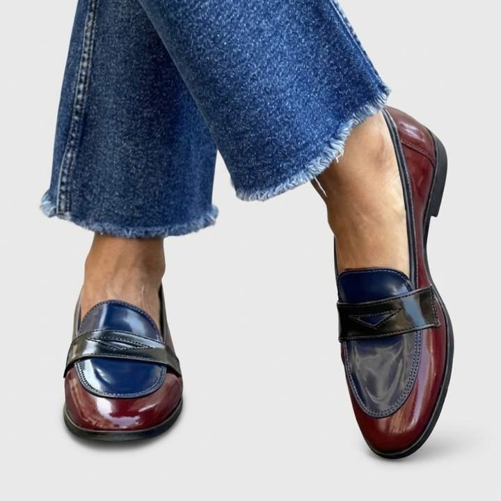 A woman wearing two-tone contrast loafers on a bright street.