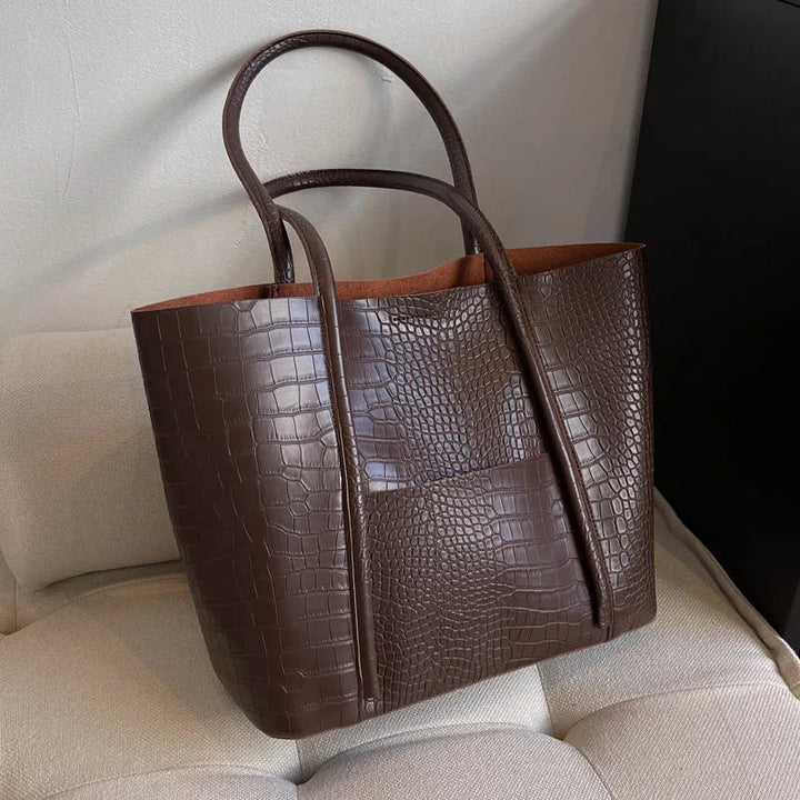 A woman carrying an elegant shoulder bag with a rich finish over one shoulder