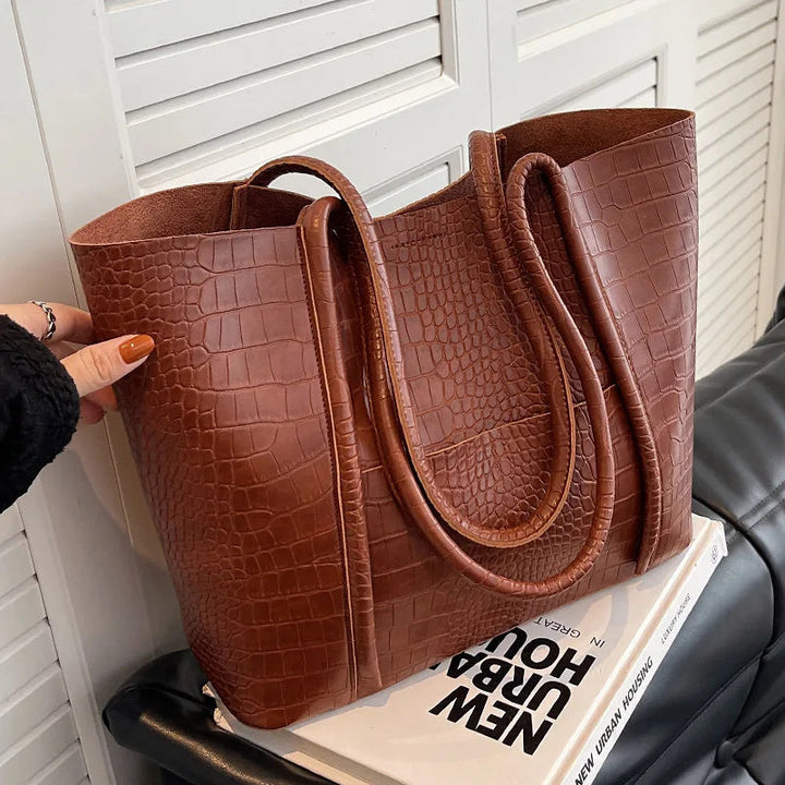 A woman carrying an elegant shoulder bag with a rich finish over one shoulder