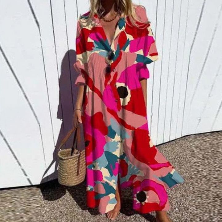 Woman wearing the Gail™ leaf print maxi dress with a button front, walking along the coast in a light breeze.