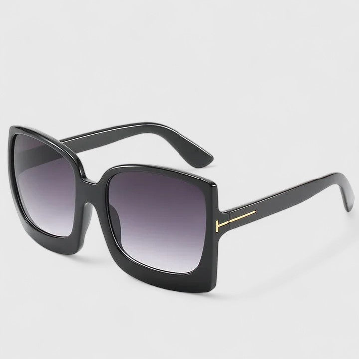 A woman on a sunny day wearing oversized gradient sunglasses, poised and glamorous.