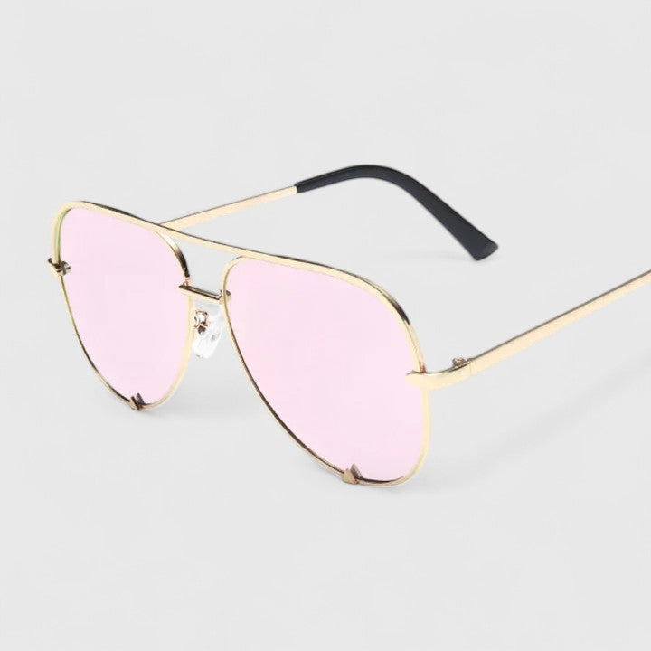 A woman by the sea wearing aviator sunglasses with gradient mirror lenses, relaxed in the sun.