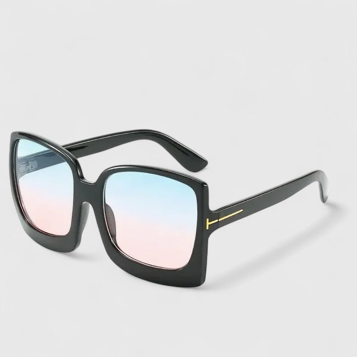 A woman on a sunny day wearing oversized gradient sunglasses, poised and glamorous.