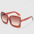 A woman on a sunny day wearing oversized gradient sunglasses, poised and glamorous.