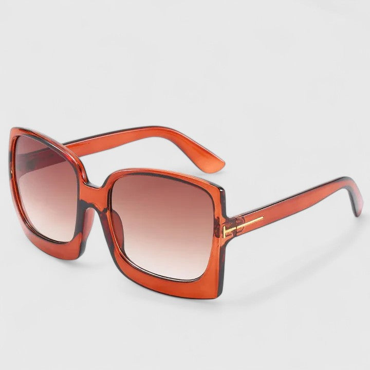 A woman on a sunny day wearing oversized gradient sunglasses, poised and glamorous.