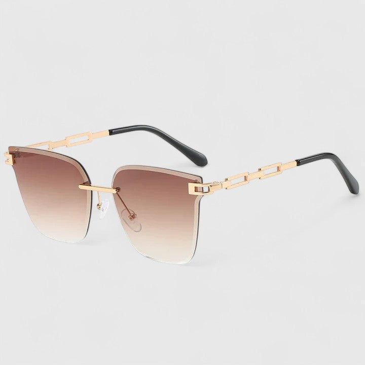 A woman wearing bold square sunglasses with brown gradient lenses and gold-tone chain-link arms.