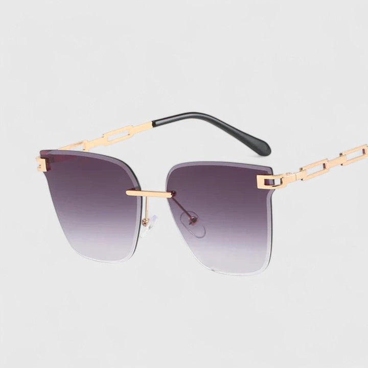 A woman wearing bold square sunglasses with brown gradient lenses and gold-tone chain-link arms.