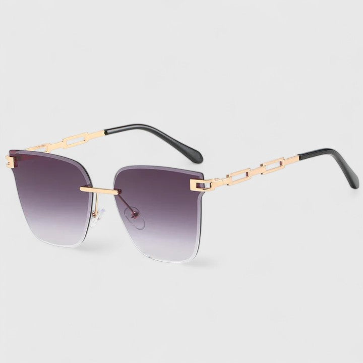 A woman wearing bold square sunglasses with brown gradient lenses and gold-tone chain-link arms.