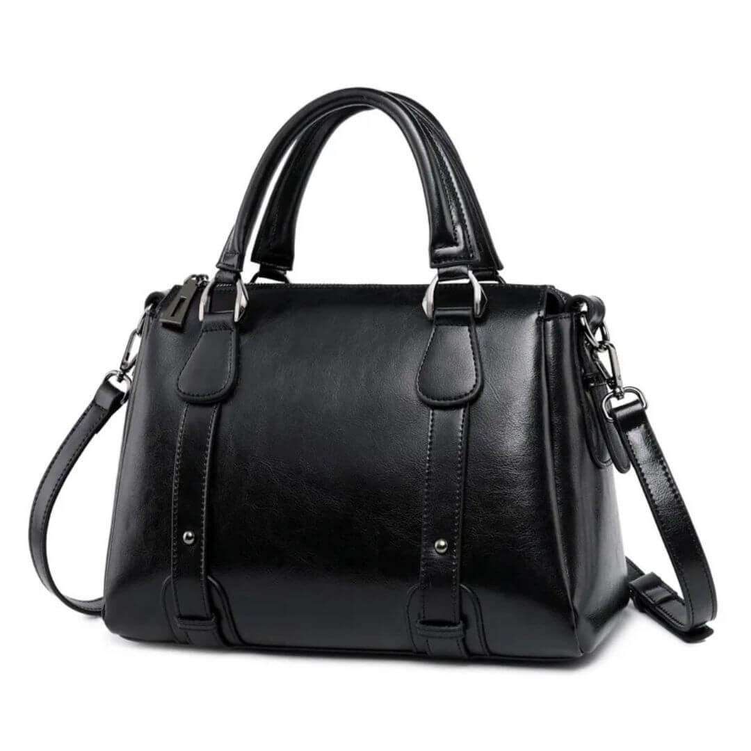 A woman with a polished structured shoulder bag resting at her hip while out for the day.