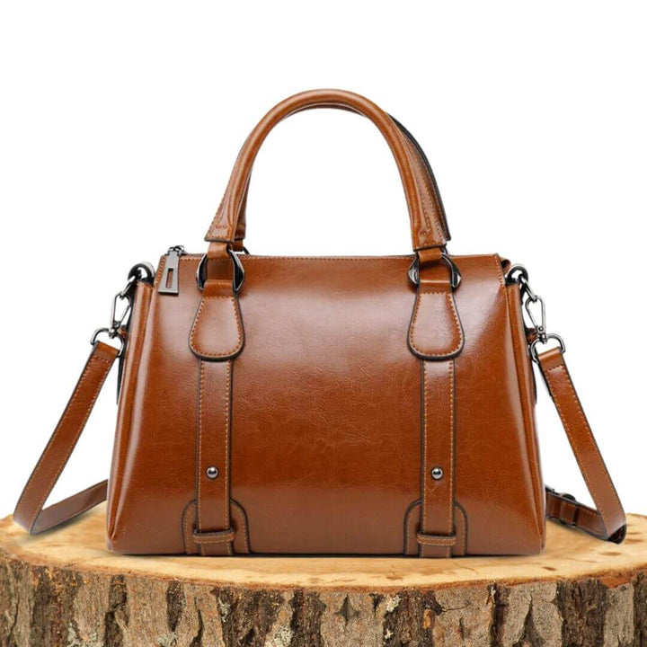 A woman with a polished structured shoulder bag resting at her hip while out for the day.