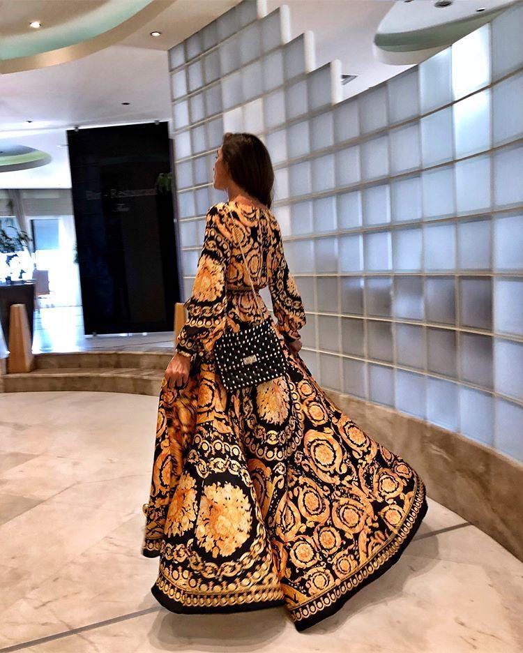 Woman at golden hour wearing the Eileen vintage print maxi dress with a waist belt and long statement sleeves.