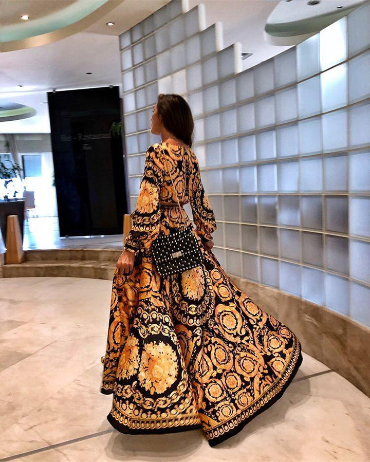 Woman at golden hour wearing the Eileen vintage print maxi dress with a waist belt and long statement sleeves.