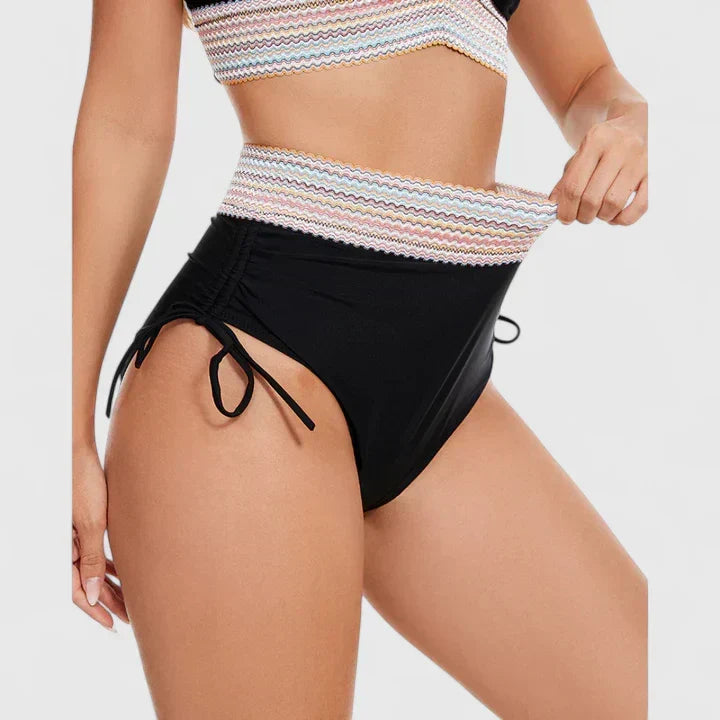 A woman wearing an elegant matching bikini set with a bold print, relaxed and confident on the beach.