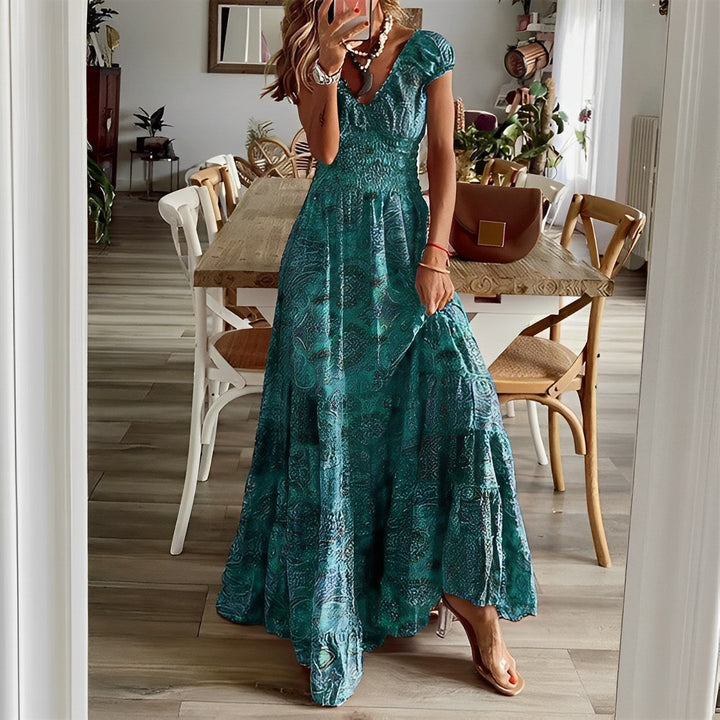 A woman wearing a patterned boho maxi dress with a gathered bodice and flowing layered skirt.