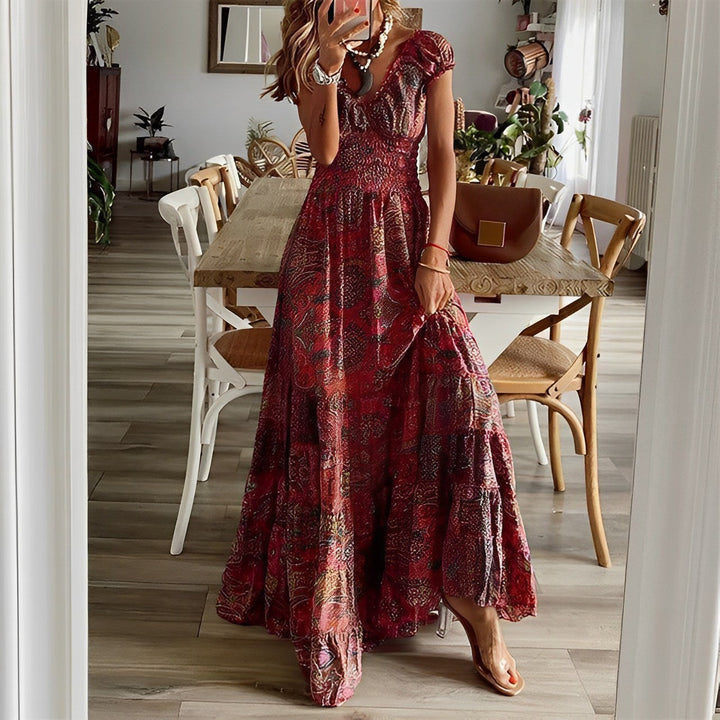 A woman wearing a patterned boho maxi dress with a gathered bodice and flowing layered skirt.