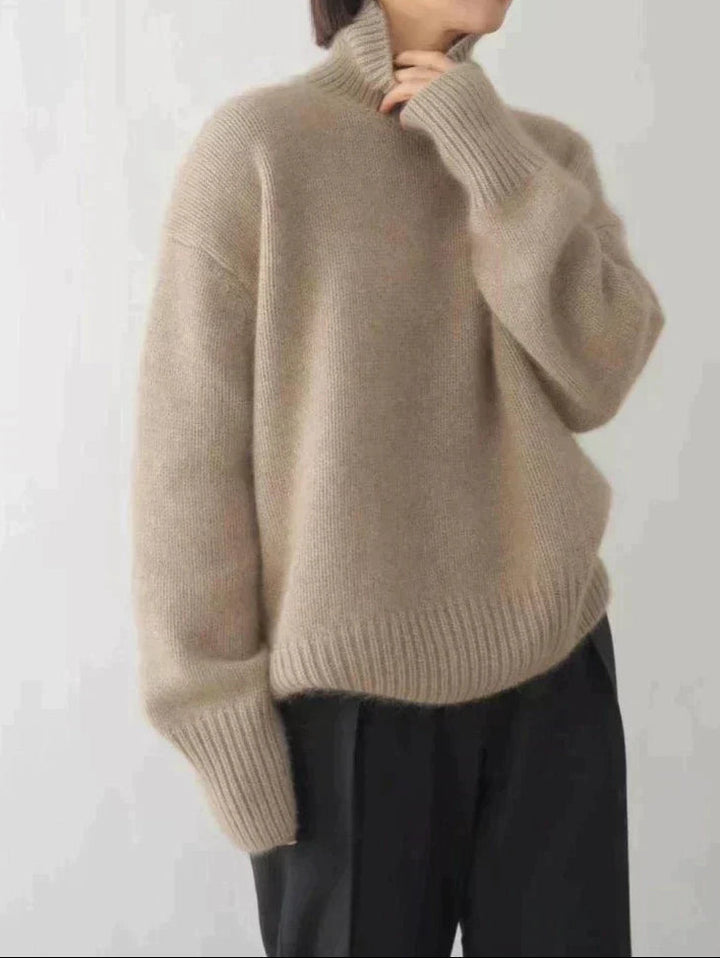 A woman wearing a beige roll-neck sweater, relaxed and warm, paired with pants.