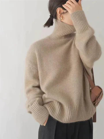 A woman wearing a beige roll-neck sweater, relaxed and warm, paired with pants.
