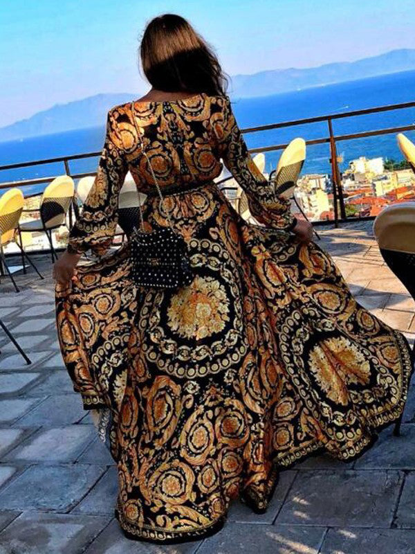 Woman at golden hour wearing the Eileen vintage print maxi dress with a waist belt and long statement sleeves.