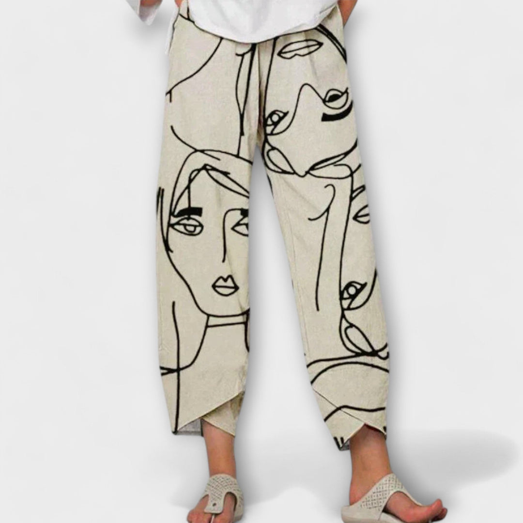 Woman wearing beige wide-leg pants with an artistic face print and a simple top.