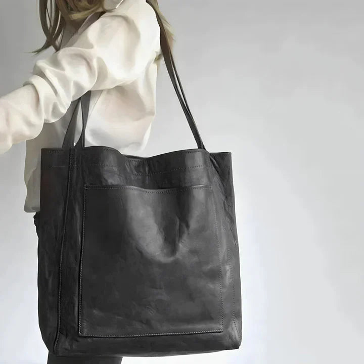 A woman holding a classic handbag with a rich finish by her side