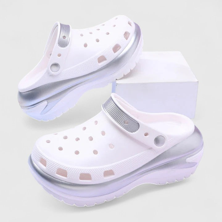 A woman walking comfortably outdoors wearing soft, cushioned orthopaedic clogs with a gentle metallic sheen.