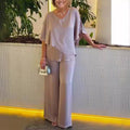 A woman wearing an asymmetric flowing top with matching wide-leg pants.