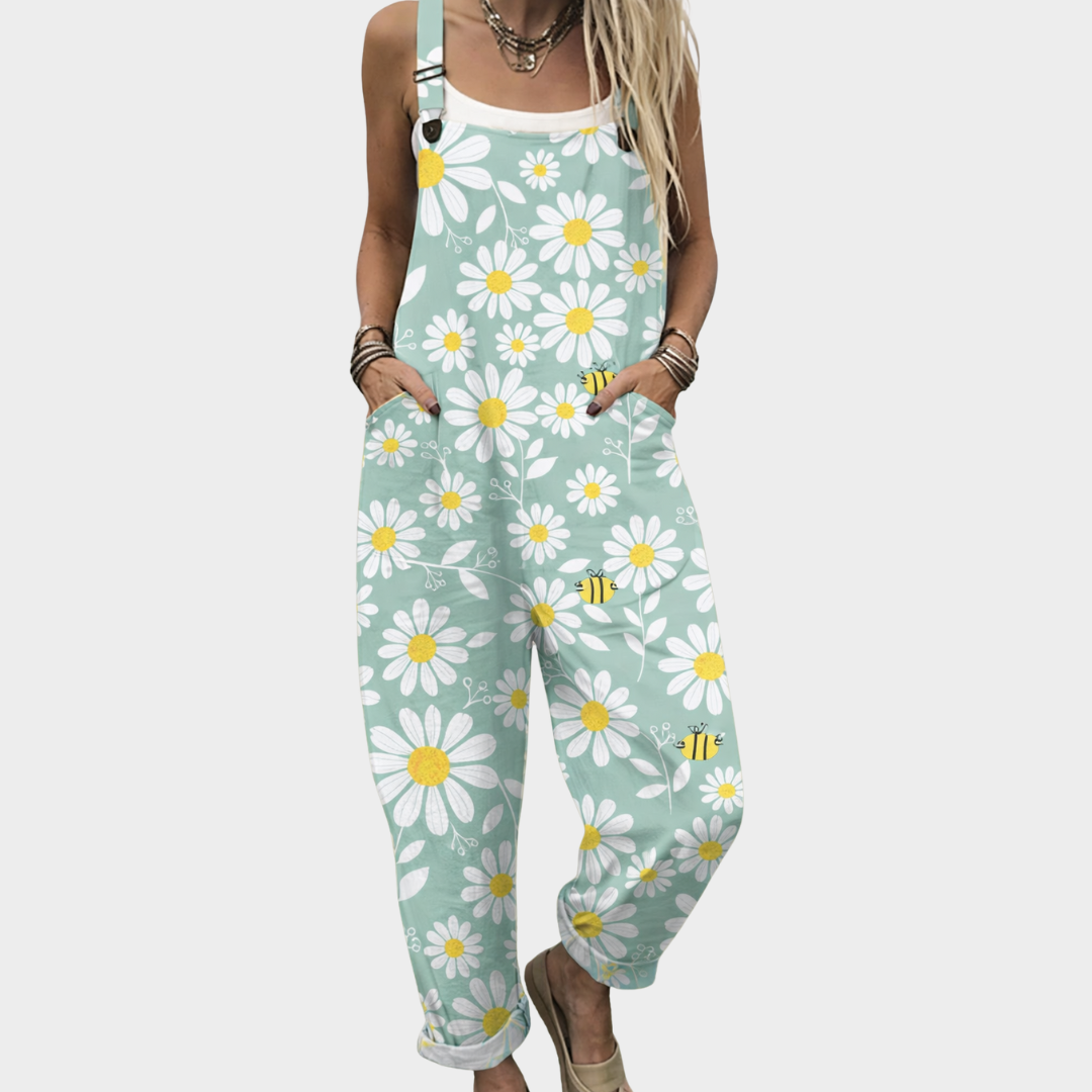 Woman wearing mint green overalls with a white daisy and bee print, adjustable straps, cheerful and relaxed.