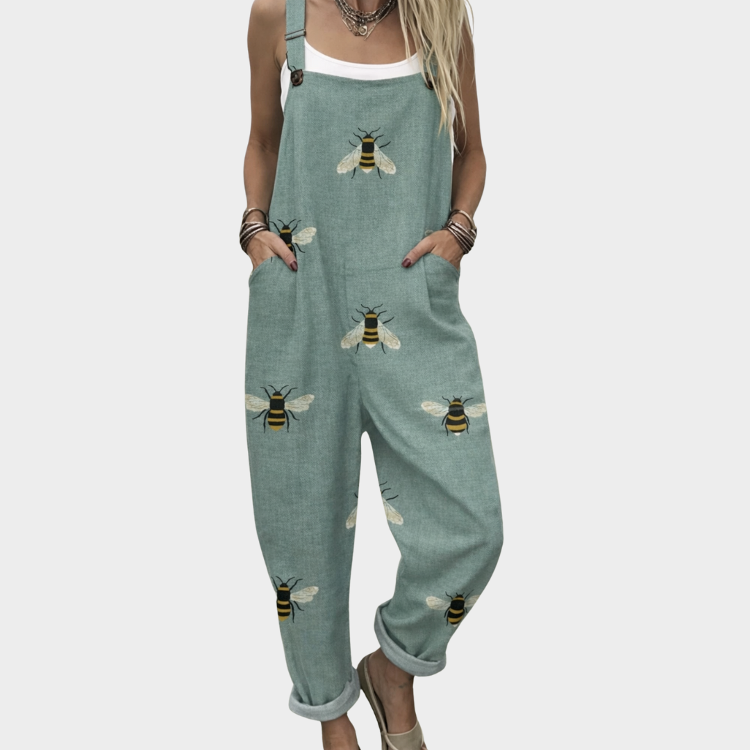 Woman wearing sage green overalls with a scattered golden bee print, adjustable straps, cheerful and relaxed.