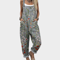 A woman wearing grey overalls covered in bright meadow flowers, daisies and poppies, with adjustable straps.