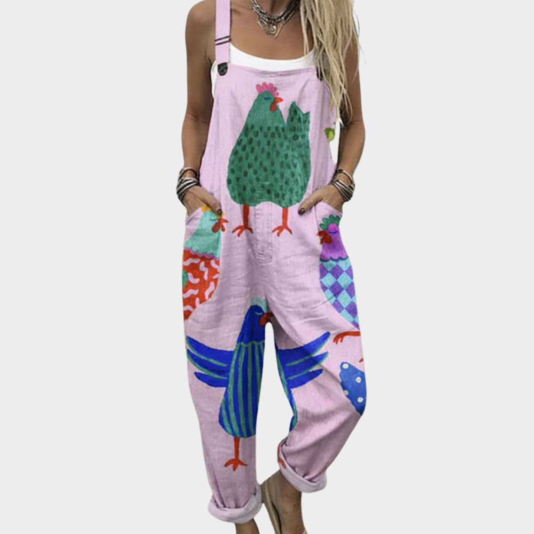Woman wearing soft pink overalls printed with big patterned hens in green and blue