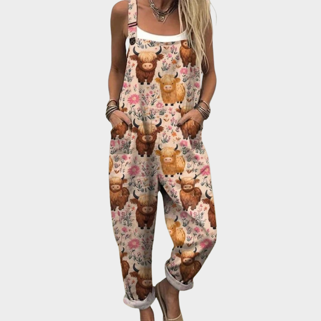 Woman wearing cream overalls with a Highland cow and floral print, adjustable straps, cheerful and relaxed.