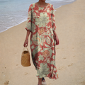A woman wearing a long, flowing patterned dress that moves gently as she walks outdoors.