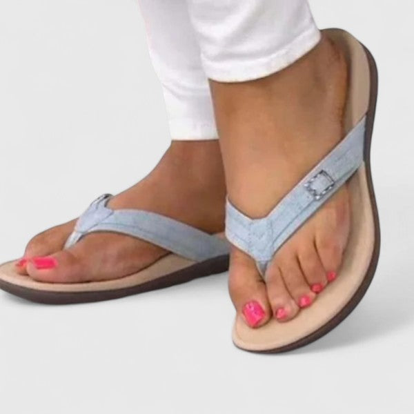 A woman in light blue lightweight flip-flops relaxing on a sunny terrace, feet light and comfortable.