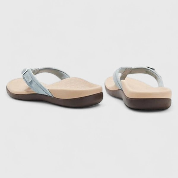 A woman in light blue lightweight flip-flops relaxing on a sunny terrace, feet light and comfortable.