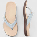 A woman in light blue lightweight flip-flops relaxing on a sunny terrace, feet light and comfortable.