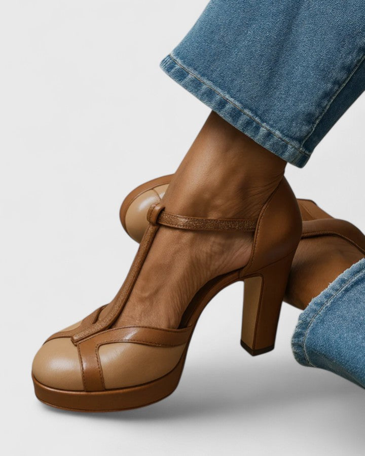 A woman wearing brown T-strap block heels, standing elegantly in a smart-casual outfit.