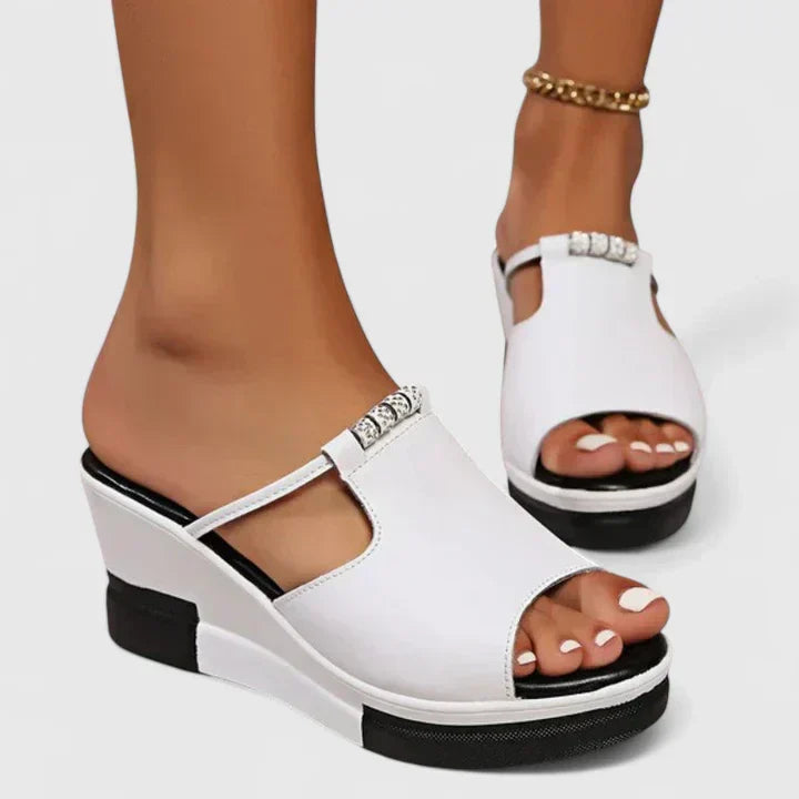 Black and white platform wedge mules with an open toe and a cut-out band across the front.