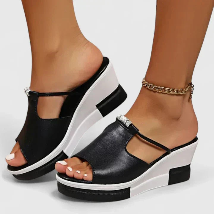 Black and white platform wedge mules with an open toe and a cut-out band across the front.