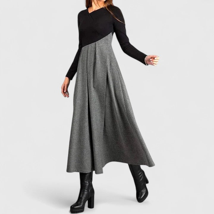Woman wearing the Linda refined dress in black-grey, posing elegantly indoors.