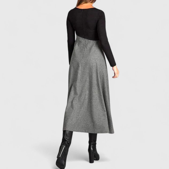Woman wearing the Linda refined dress in black-grey, posing elegantly indoors.