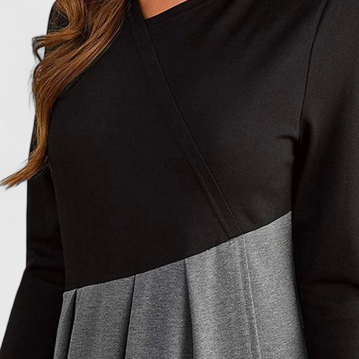 Woman wearing the Linda refined dress in black-grey, posing elegantly indoors.