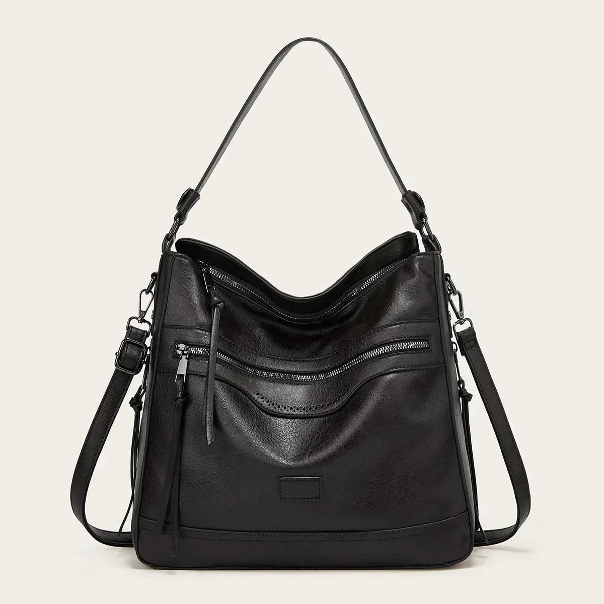 A soft brown vintage shoulder bag with zip pockets and tassel pulls, carried on the shoulder in town.