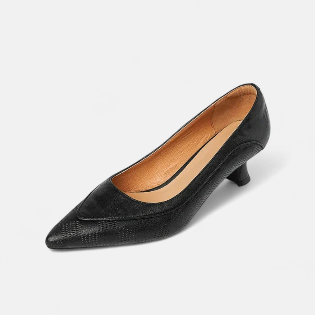 A woman wearing black pointed kitten-heel pumps with a subtle embossed finish.