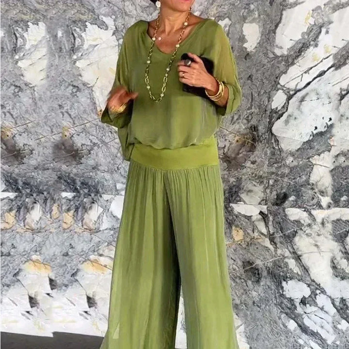 A woman wearing a flowing lounge two-piece set with a V-neck top and wide-leg pants.