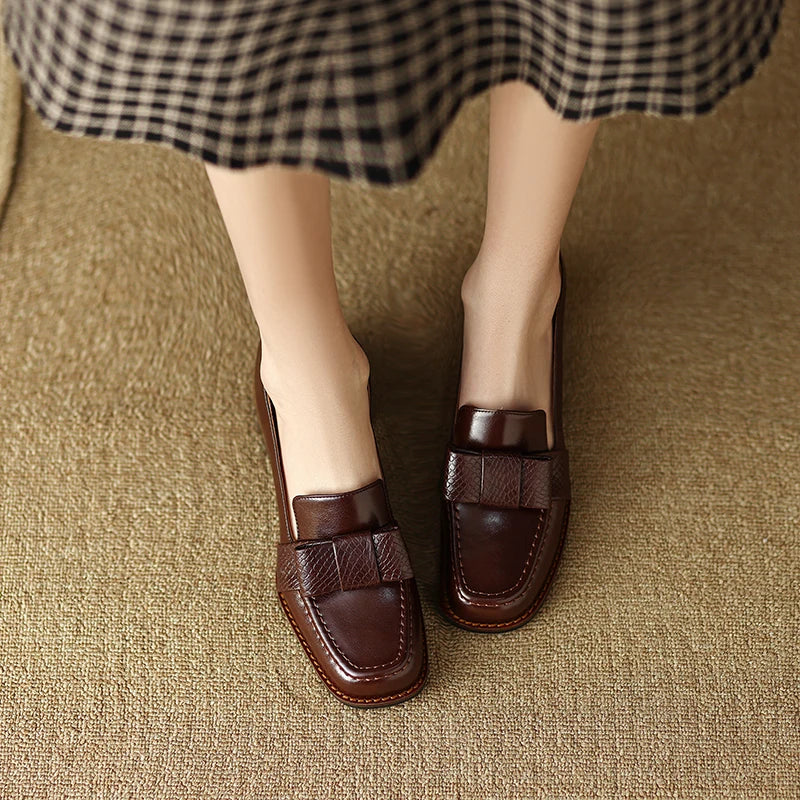 A woman wearing classic loafers with a subtle knot detail and tailored pants