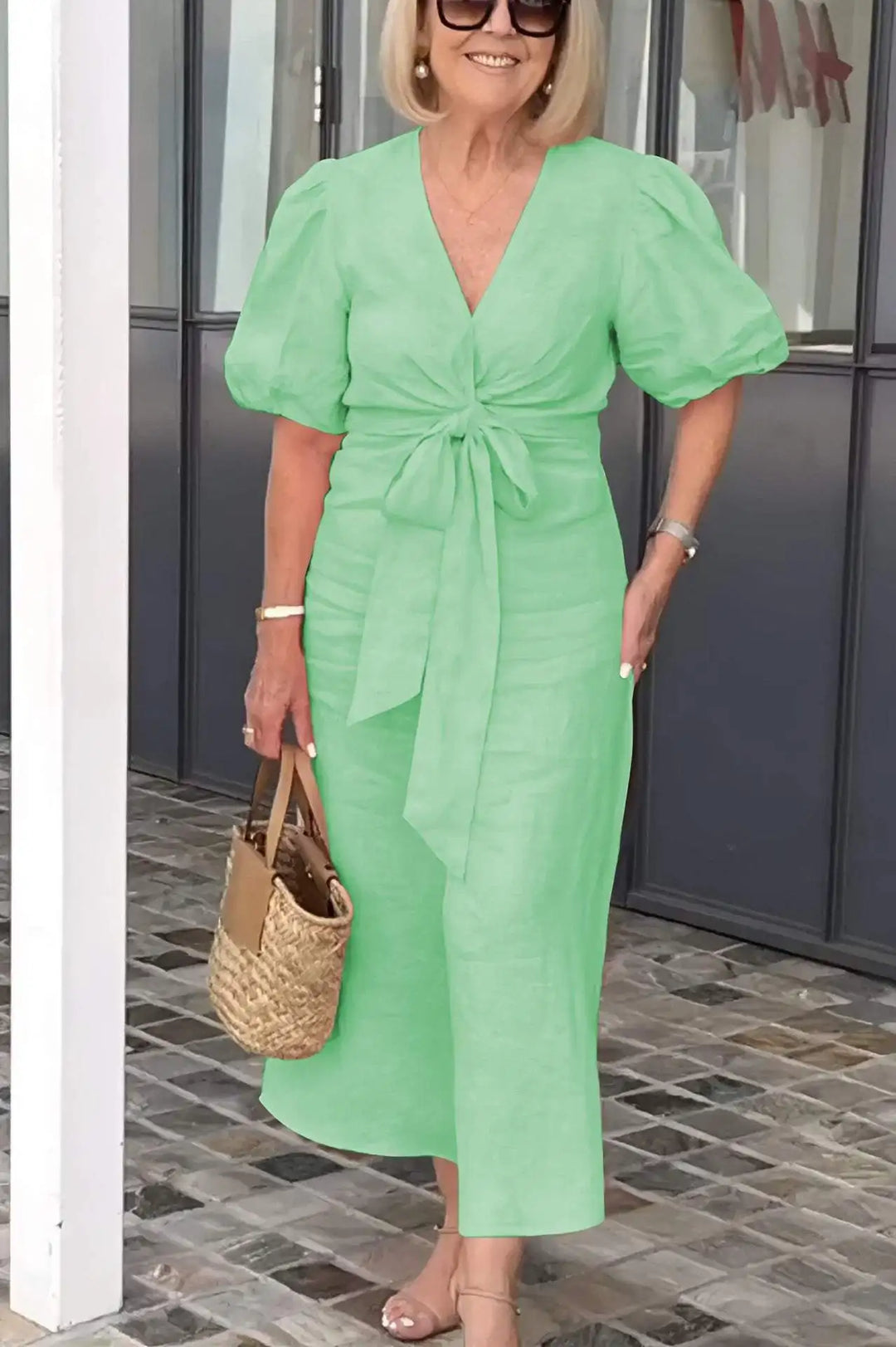 Woman wearing the Christina bow-front midi dress with puff sleeves at a garden party.
